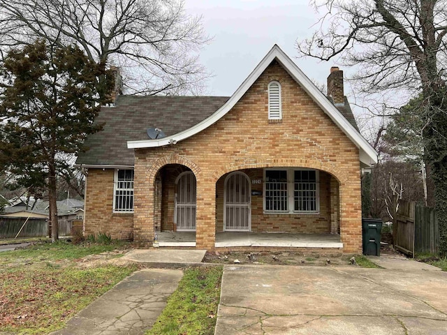 3224 W 11th St, Little Rock, AR 72204 - tudor home with brick siding, a porch, a chimney, and fence