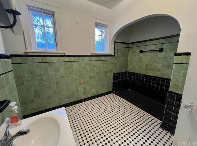3224 W 11th St, Little Rock, AR 72204 - bathroom featuring tile walls, a sink, a shower, wainscoting, and tile patterned flooring