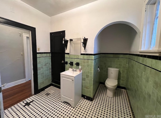 3224 W 11th St, Little Rock, AR 72204 - half bathroom with tile walls, a wainscoted wall, toilet, vanity, and tile patterned floors
