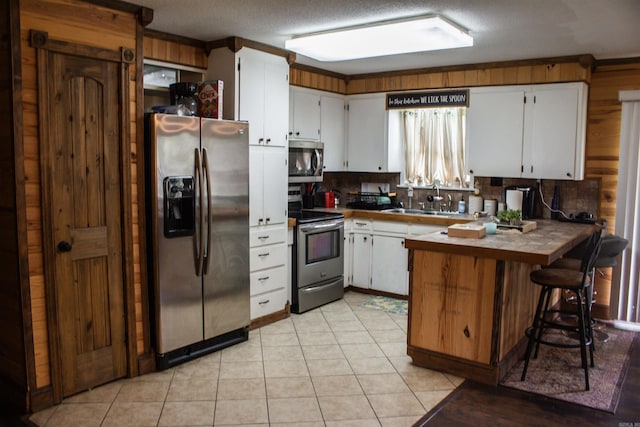 100 Elizabeth St, Prescott, AR 71857 - kitchen featuring appliances with stainless steel finishes, a sink, a peninsula, white cabinetry, and light tile patterned floors