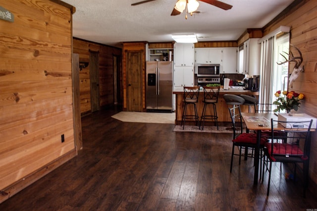100 Elizabeth St, Prescott, AR 71857 - dining space featuring a ceiling fan, wood walls, and dark wood finished floors