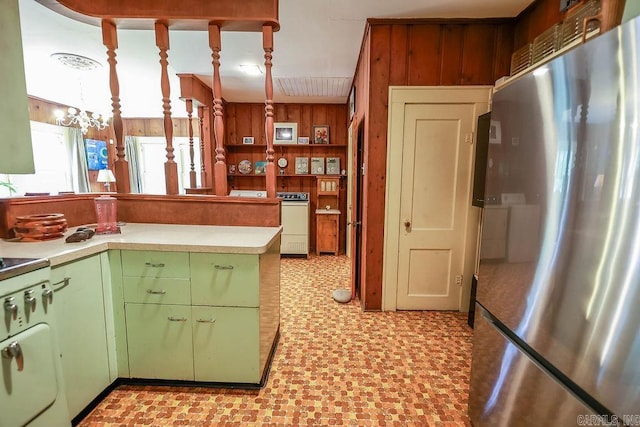 608 E 5th St, El Dorado, AR 71730 - kitchen with freestanding refrigerator, green cabinetry, wood walls, light countertops, and a chandelier