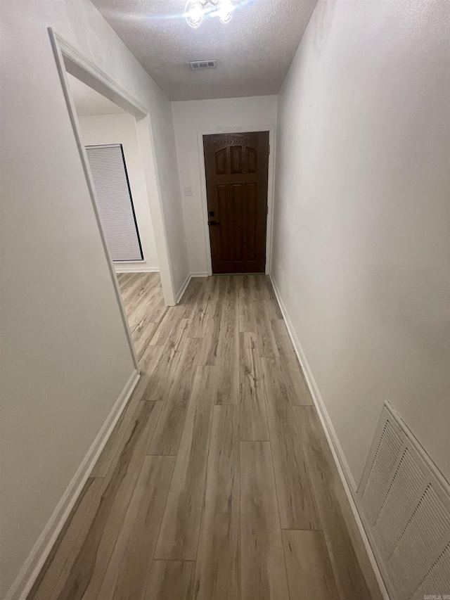 11808 Saint Charles Blvd, Little Rock, AR 72211 - hallway with light wood finished floors, baseboards, and a textured ceiling
