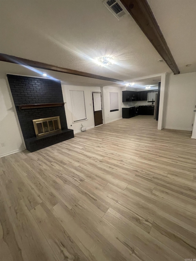 11808 Saint Charles Blvd, Little Rock, AR 72211 - unfurnished living room with a fireplace, light wood finished floors, baseboards, and beamed ceiling