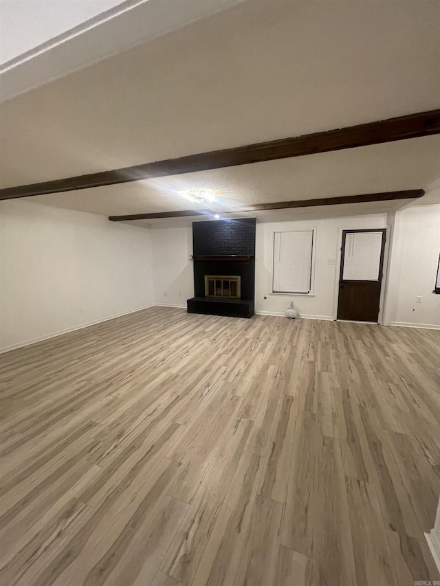 11808 Saint Charles Blvd, Little Rock, AR 72211 - unfurnished living room with beamed ceiling, light wood-type flooring, a fireplace, and baseboards
