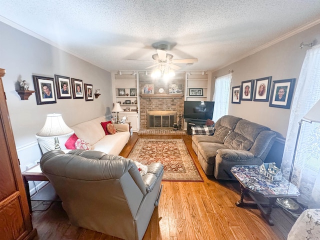 53 White Oak Cir, Searcy, AR 72143 - living room with a textured ceiling, wood finished floors, a ceiling fan, a brick fireplace, and ornamental molding