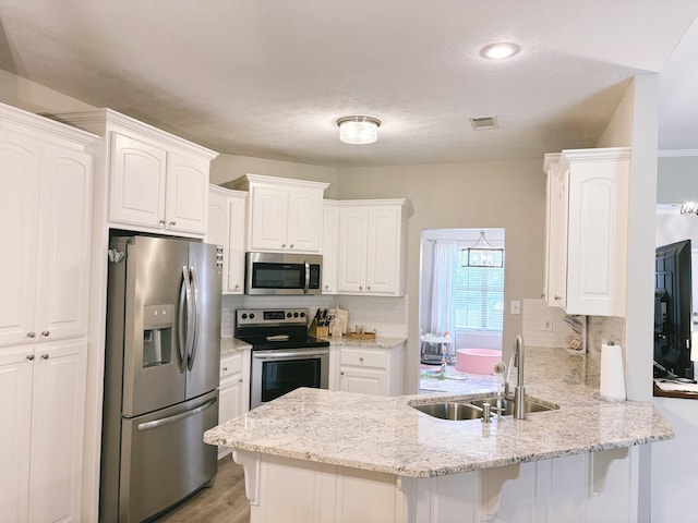 1808 Hidden Crk, Sherwood, AR 72120 - kitchen with appliances with stainless steel finishes, a sink, a peninsula, tasteful backsplash, and white cabinets