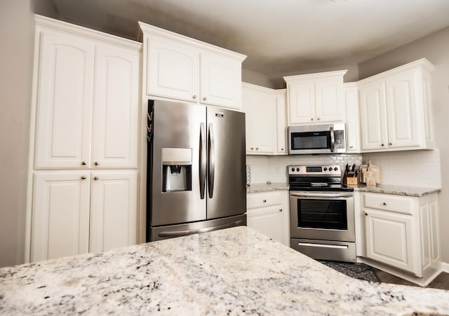 1808 Hidden Crk, Sherwood, AR 72120 - kitchen featuring stainless steel appliances, tasteful backsplash, white cabinetry, and light stone countertops