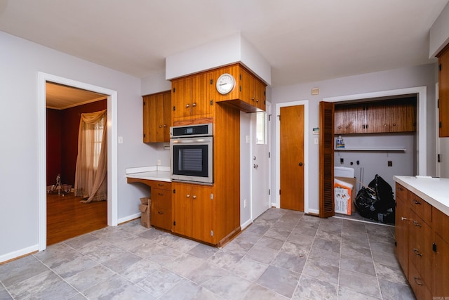 17 Wingate Dr, Little Rock, AR 72205 - kitchen featuring stainless steel oven, light countertops, brown cabinetry, baseboards, and light stone finish flooring