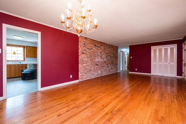 17 Wingate Dr, Little Rock, AR 72205 - empty room with a sink, a chandelier, wood finished floors, brick wall, and baseboards