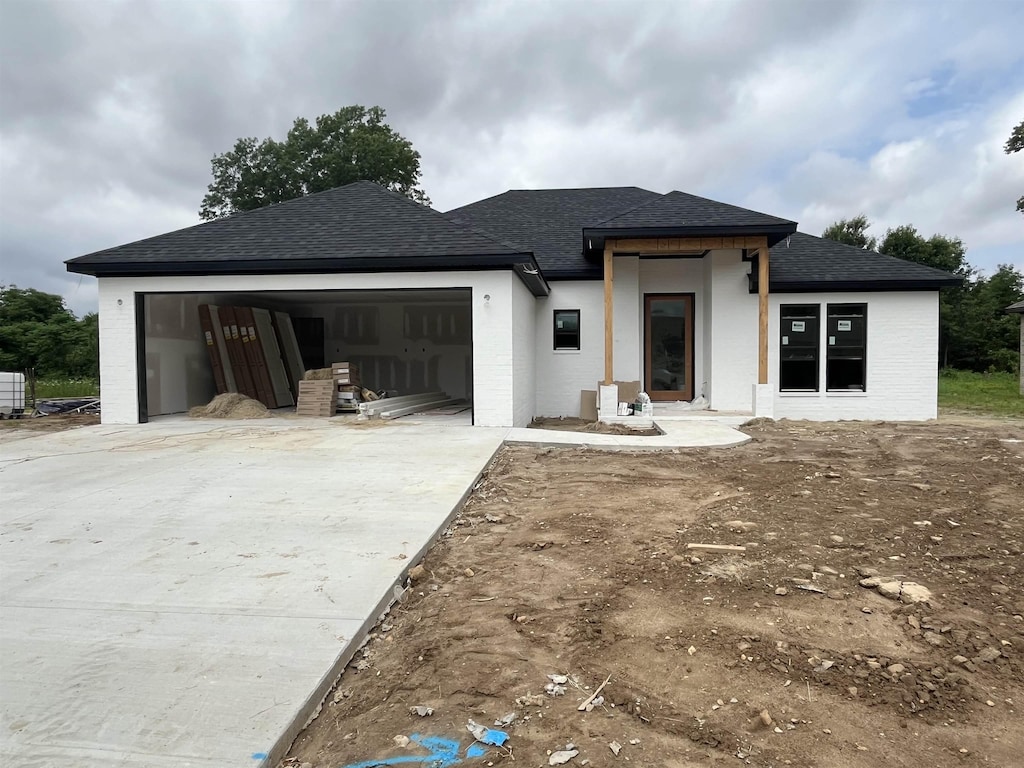 view of front of property with roof with shingles, concrete driveway, and a garage