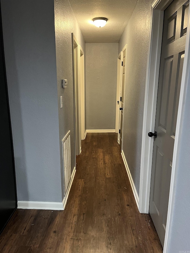 4903 Wise St, Paragould, AR 72450 - hallway featuring a textured wall, dark wood-style floors, baseboards, and a textured ceiling