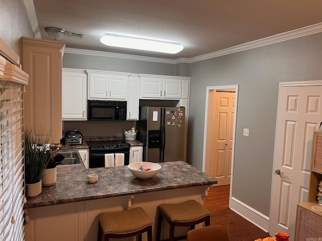 kitchen with black appliances, a peninsula, crown molding, a breakfast bar area, and dark wood-style flooring