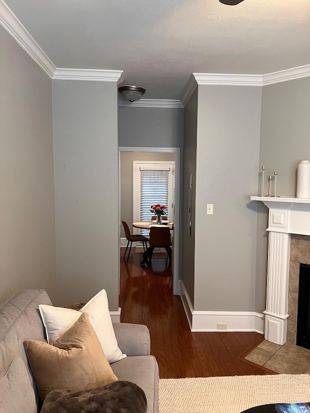 living area with ornamental molding, wood finished floors, baseboards, and a fireplace