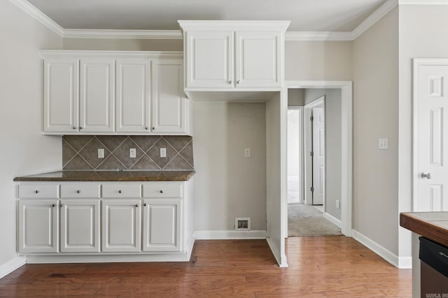 113 Shady Dr, Maumelle, AR 72113 - kitchen with white cabinetry, light wood-style flooring, decorative backsplash, dark countertops, and ornamental molding