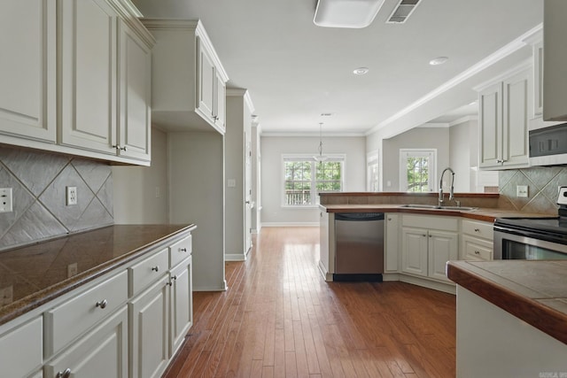 113 Shady Dr, Maumelle, AR 72113 - kitchen featuring appliances with stainless steel finishes, a sink, a peninsula, dark wood-style floors, and tasteful backsplash