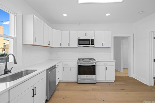 2501 S Maple St, Little Rock, AR 72204 - kitchen featuring stainless steel appliances, a sink, white cabinets, light countertops, and backsplash