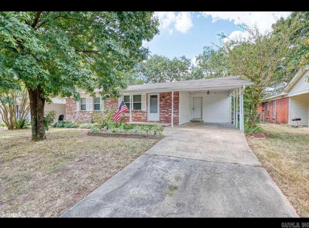 single story home with a front lawn, driveway, an attached carport, and brick siding