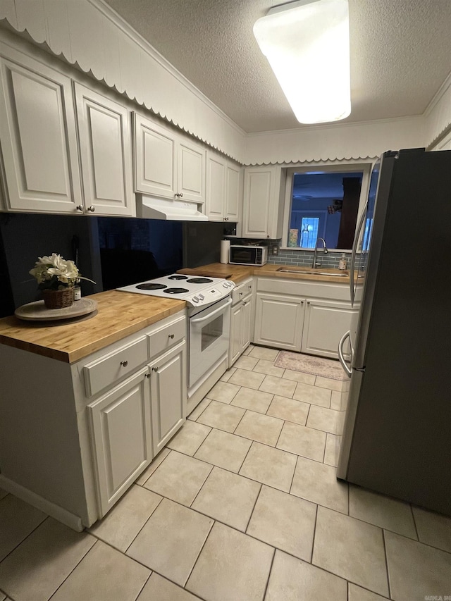 kitchen featuring freestanding refrigerator, electric range, butcher block countertops, a textured ceiling, and a sink