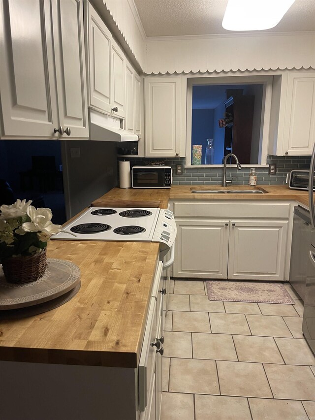 kitchen featuring butcher block countertops, a sink, black microwave, white cabinets, and decorative backsplash