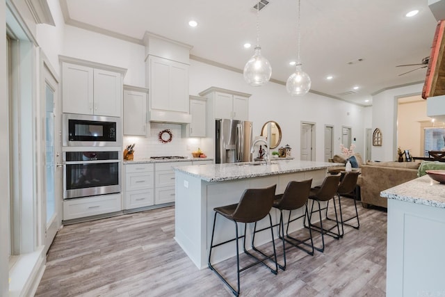 92 Hudson Dr, Sheridan, AR 72150 - kitchen with appliances with stainless steel finishes, open floor plan, a breakfast bar area, decorative backsplash, and light wood-style floors
