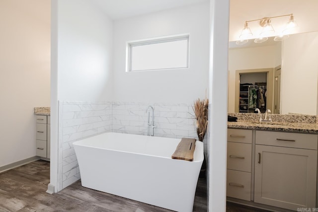 92 Hudson Dr, Sheridan, AR 72150 - bathroom featuring vanity, tile walls, a walk in closet, wood finished floors, and a soaking tub