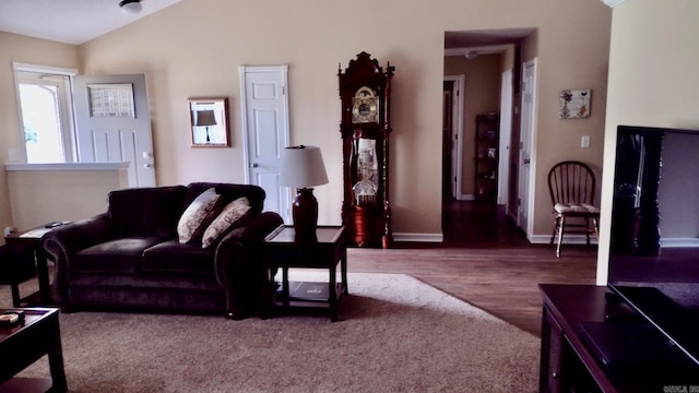 living area featuring lofted ceiling, wood finished floors, and baseboards