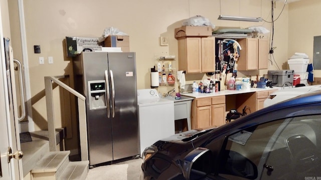 garage featuring stainless steel fridge with ice dispenser, washer / dryer, and a sink