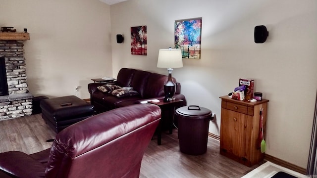 living area with wood finished floors, a fireplace, and baseboards