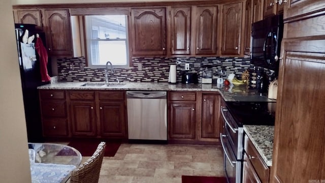 kitchen featuring stainless steel appliances, a sink, decorative backsplash, light stone counters, and light floors