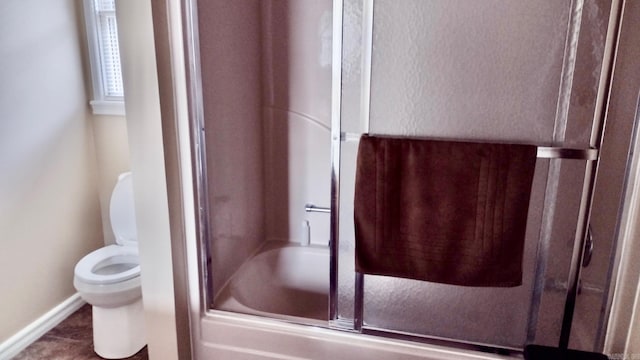 bathroom with toilet, baseboards, and enclosed tub / shower combo