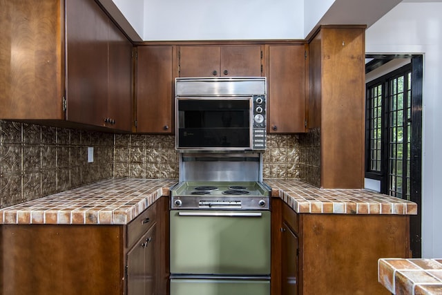 2108 Beechwood, Little Rock, AR 72207 - kitchen with electric range, stainless steel microwave, tile countertops, and tasteful backsplash