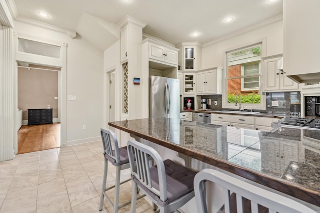 121 N Woodrow St, Little Rock, AR 72205 - kitchen featuring stainless steel appliances, a sink, a breakfast bar area, crown molding, and decorative backsplash