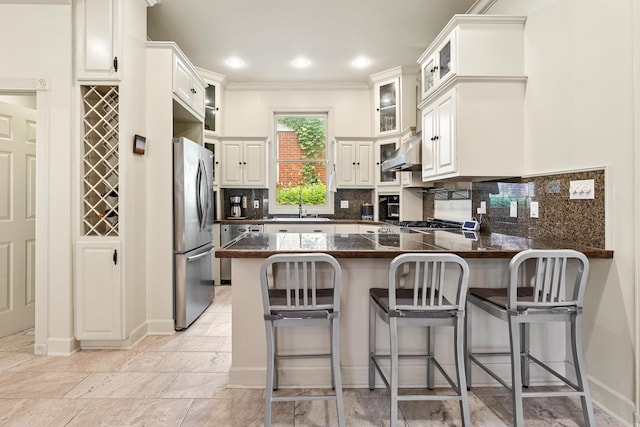 121 N Woodrow St, Little Rock, AR 72205 - kitchen featuring appliances with stainless steel finishes, a peninsula, a breakfast bar area, glass insert cabinets, and ventilation hood