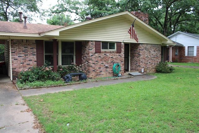 view of front of property featuring brick siding, a chimney, a front yard, and a shingled roof