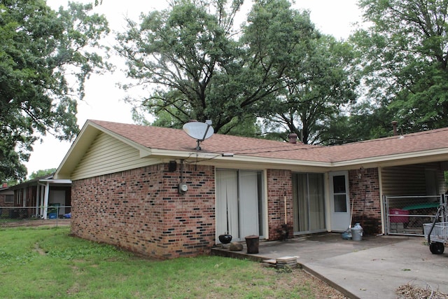 back of house featuring brick siding and roof with shingles