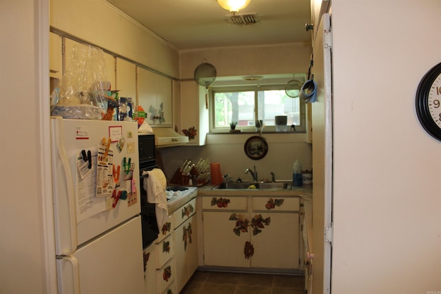 kitchen with freestanding refrigerator, a sink, under cabinet range hood, light countertops, and dark tile patterned floors