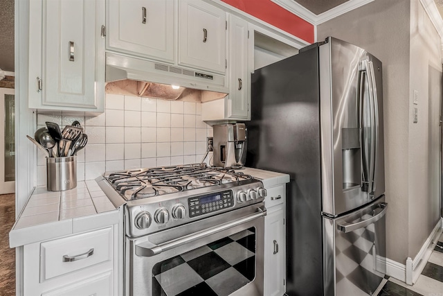 77 Stoneledge Dr, Maumelle, AR 72113 - kitchen featuring appliances with stainless steel finishes, tile counters, under cabinet range hood, crown molding, and backsplash