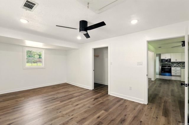 13512 Peters Rd, Cabot, AR 72023 - unfurnished bedroom featuring dark wood-type flooring, baseboards, recessed lighting, a ceiling fan, and a walk in closet