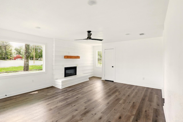 13512 Peters Rd, Cabot, AR 72023 - unfurnished living room featuring healthy amount of natural light, dark wood-type flooring, a large fireplace, and a ceiling fan
