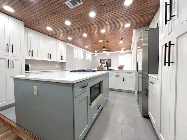 1701 N University, Little Rock, AR 72207 - kitchen featuring wood ceiling, black microwave, a kitchen island, white cabinets, and stainless steel gas cooktop