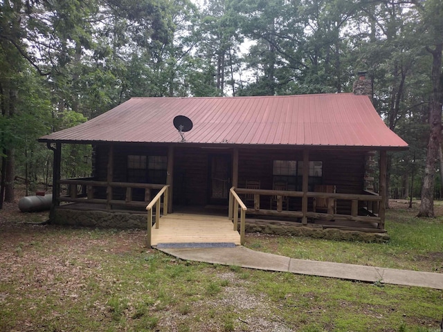 cabin featuring covered porch, metal roof, and a chimney