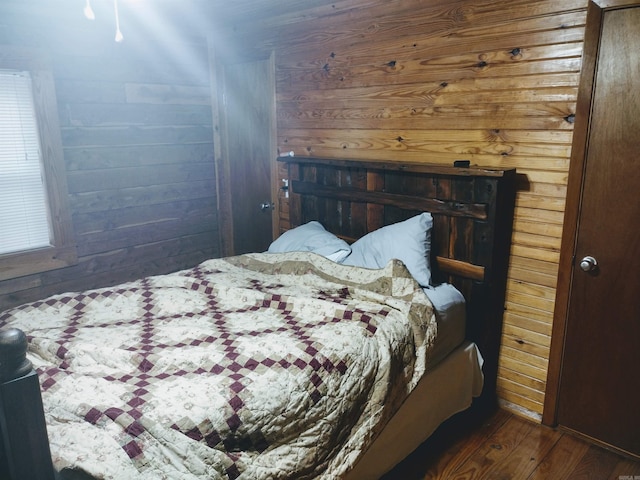 bedroom with wood walls and wood finished floors