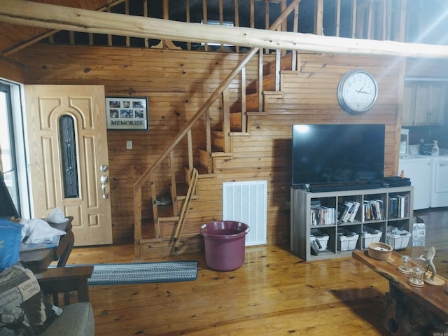 living room with washing machine and dryer, wooden walls, stairs, wood finished floors, and high vaulted ceiling