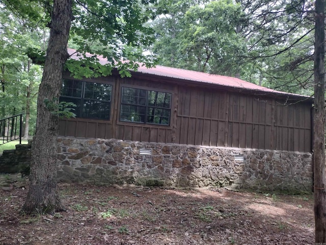 view of home's exterior featuring stone siding, metal roof, and board and batten siding