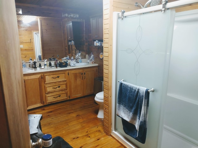 full bathroom with a shower stall, hardwood / wood-style floors, wood walls, and double vanity