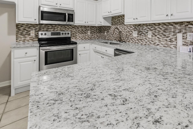 14 Woodbridge, Cabot, AR 72023 - kitchen featuring appliances with stainless steel finishes, a sink, light stone countertops, white cabinets, and tasteful backsplash