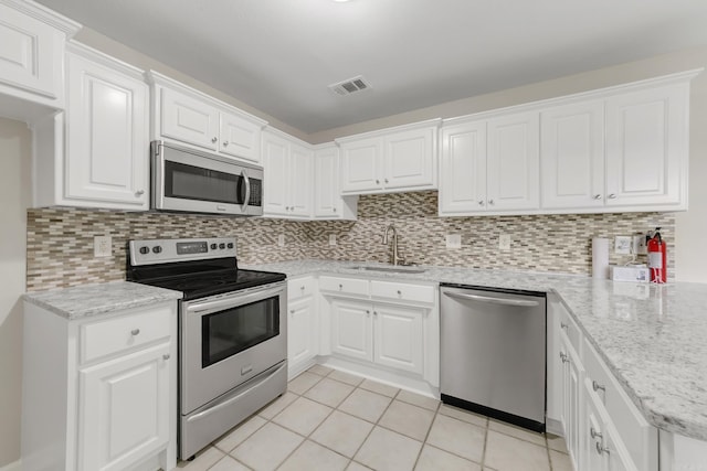 14 Woodbridge, Cabot, AR 72023 - kitchen with stainless steel appliances, a sink, light tile patterned floors, white cabinetry, and backsplash