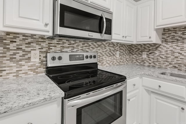 14 Woodbridge, Cabot, AR 72023 - kitchen featuring appliances with stainless steel finishes, white cabinets, tasteful backsplash, and light stone counters