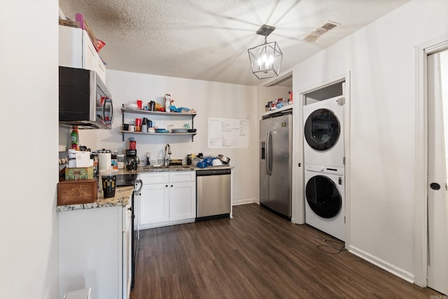 1403 Scott, Conway, AR 72032 - kitchen with appliances with stainless steel finishes, estacked washer and dryer, open shelves, dark wood-type flooring, and a textured ceiling